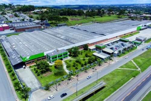 Vista aérea de uma unidade industrial da Klabin com galpões, áreas verdes e acesso viário ao redor.