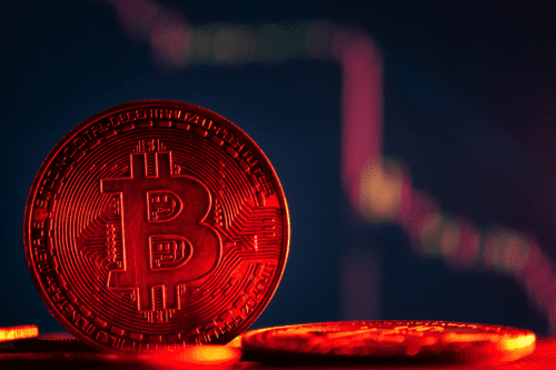 Moedas com o símbolo do Bitcoin em fundo vermelho e gráfico de ações de criptomoedas.