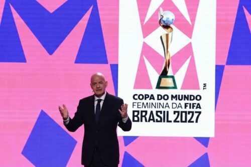 Gianni Infantino, presidente da FIFA, de pé em um palco gesticulando com as mãos.
