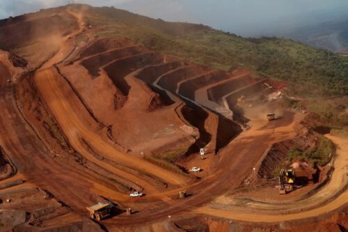 Vista aérea de um grande canteiro de obras de infraestrutura em terreno montanhoso.