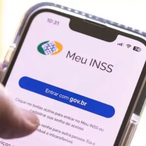 Close-up de uma mão segurando um smartphone que exibe a tela inicial do aplicativo "Meu INSS".