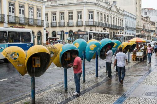 Uma fileira de telefones públicos (orelhões) nas cores amarelo e azul.