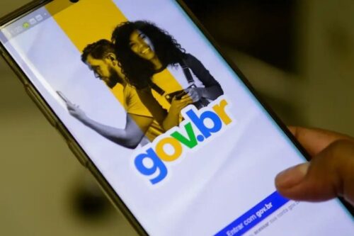 Foto em close de uma pessoa segurando um smartphone que exibe a tela de login do portal gov.br.