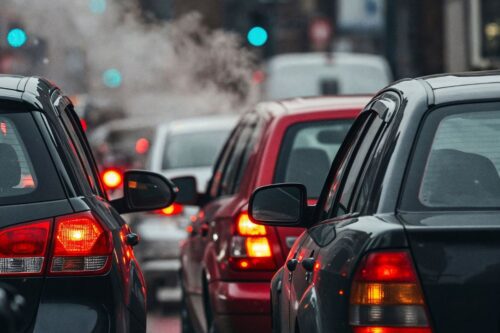: Visão traseira de diversos carros enfileirados em um congestionamento urbano.