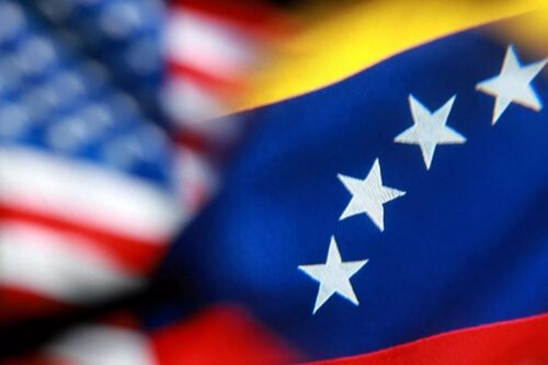 Sobreposição das bandeiras dos Estados Unidos e da Venezuela em um efeito de desfoque, destacando as estrelas da bandeira venezuelana em primeiro plano.