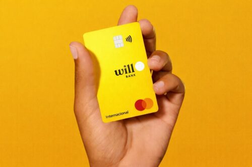 Cartão amarelo do Will Bank sendo segurado por uma mão, com logo da instituição em destaque após liquidação do Will Bank
