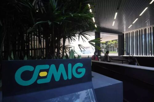 Fachada da Cemig com logotipo em destaque na entrada do prédio, ambiente moderno e pessoas circulando no local.
