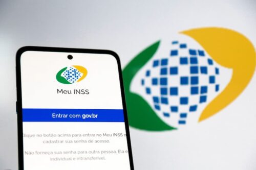 Tela do aplicativo Meu INSS em celular com logotipo ao fundo, ilustrando instabilidade e acesso indisponível, representando Meu INSS fora do ar.