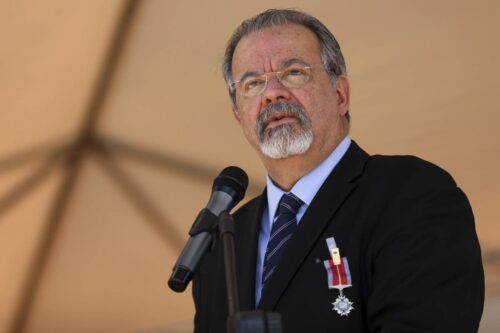 Raul Jungmann discursa ao microfone em cerimônia oficial, usando terno e medalha, em ambiente institucional ao ar livre.