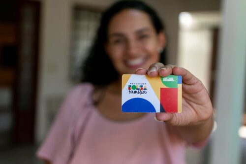 Mulher segura cartão do Bolsa Família em destaque, imagem usada para ilustrar o calendário bolsa família 2026 e o benefício social.