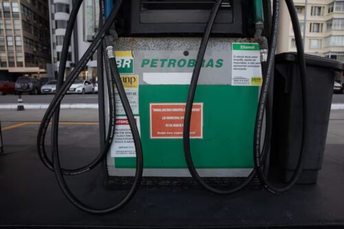 Petrobras reduz preço da gasolina em posto de combustível, com bomba de abastecimento e mangueiras visíveis.