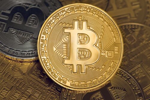 Moedas de Bitcoin empilhadas, com símbolo dourado em destaque, representando o mercado de criptomoedas e ativos digitais.
