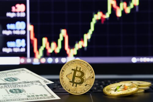 Bitcoin e dólares em frente a gráfico de preços, ilustrando traders de criptomoedas analisando o mercado financeiro.