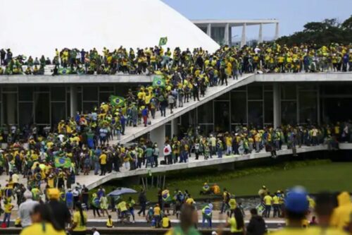 Grande multidão de manifestantes vestidos de verde e amarelo ocupando as rampas e a parte externa do Congresso Nacional em Brasília. Algumas pessoas carregam bandeiras do Brasil. Vista panorâmica dos atos ocorridos na Praça dos Três Poderes.