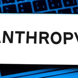 Smartphone exibindo o logotipo da empresa de inteligência artificial "ANTHROP\C" em letras pretas sobre um fundo branco. O aparelho está posicionado sobre o teclado retroiluminado em azul de um notebook.