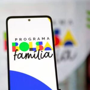 Primeiro plano de um smartphone exibindo o logotipo colorido do 'Programa Bolsa Família'.