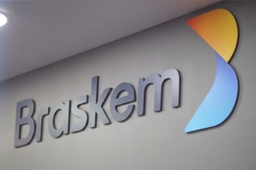 Logotipo da empresa Braskem fixado em uma parede cinza.