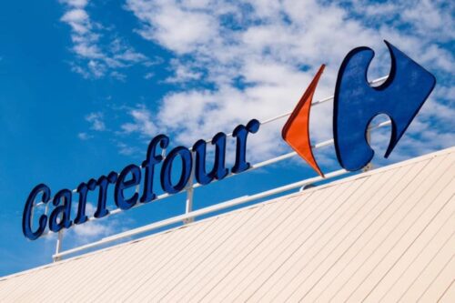 Letreiro externo da marca Carrefour instalado no topo de um telhado branco.