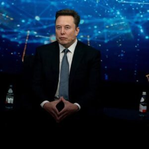 Fotografia de Elon Musk sentado em um palco durante um evento.