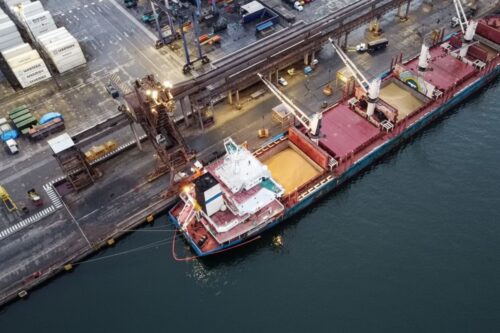 Vista aérea de um navio cargueiro atracado em um porto industrial durante o entardecer.
