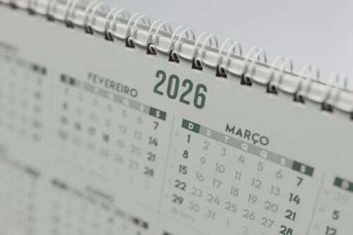 Fotografia em close-up de um calendário de mesa espiral branco, com foco centralizado no ano "2026".