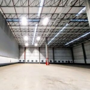 Ampla visão interna de um galpão logístico industrial vazio.