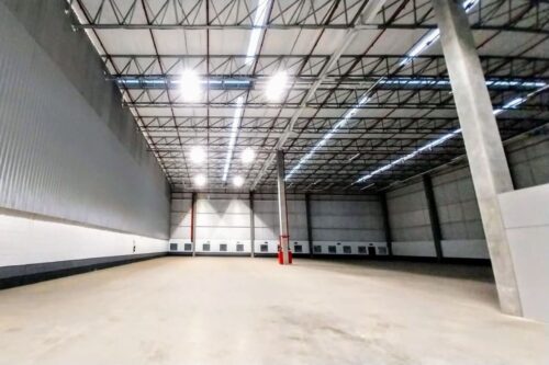 Ampla visão interna de um galpão logístico industrial vazio.