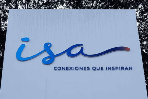Logotipo da empresa ISA instalado em um painel branco ao ar livre. A palavra 'isa' aparece em letras cursivas azuis, seguida pela frase 'CONEXIONES QUE INSPIRAN' em letras maiúsculas logo abaixo. Folhagens escuras são visíveis ao fundo.