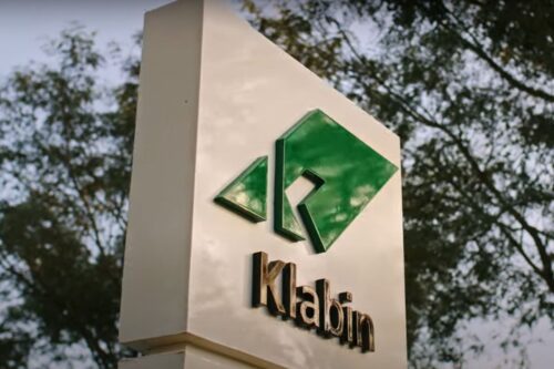 Fotografia em ângulo inferior de um totem branco com o logotipo da Klabin.