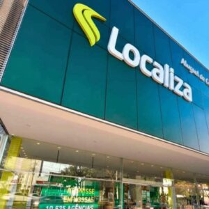 Fachada moderna de uma agência da Localiza em ângulo contra-picado. O destaque é o painel verde escuro com o logotipo da empresa em amarelo e branco.