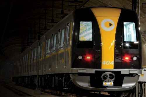 O trem tem a frente predominantemente preta com uma faixa vertical central em amarelo vibrante.