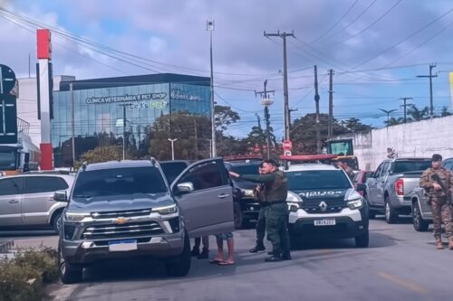 Fotografia em plano médio de uma abordagem policial em uma via urbana.