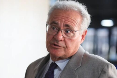 Retrato em plano médio do senador Renan Calheiros. Ele é um homem de pele clara, cabelos grisalhos e usa óculos de grau com armação fina.