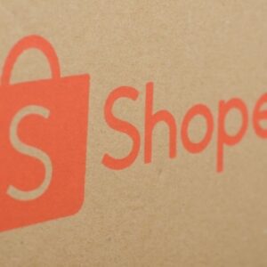 Close-up do logotipo da Shopee impresso em uma caixa de papelão parda.