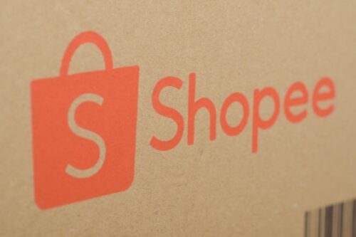Close-up do logotipo da Shopee impresso em uma caixa de papelão parda.
