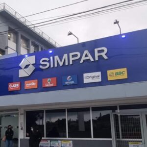 Fachada de um prédio da holding Simpar, com um grande painel azul exibindo o nome da marca e os logotipos de suas subsidiárias, como JSL, Movida, Vamos e Banco ABC.