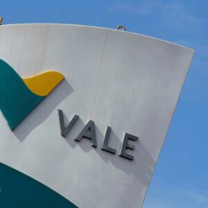 Placa em ângulo diagonal exibindo o logotipo da mineradora Vale. A estrutura é branca com a palavra "VALE" escrita em letras cinza metálicas.