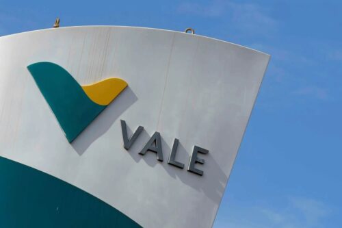 Placa em ângulo diagonal exibindo o logotipo da mineradora Vale. A estrutura é branca com a palavra "VALE" escrita em letras cinza metálicas.