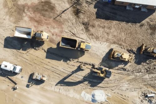 Vista aérea de um canteiro de obras ou área de mineração com terra batida clara.