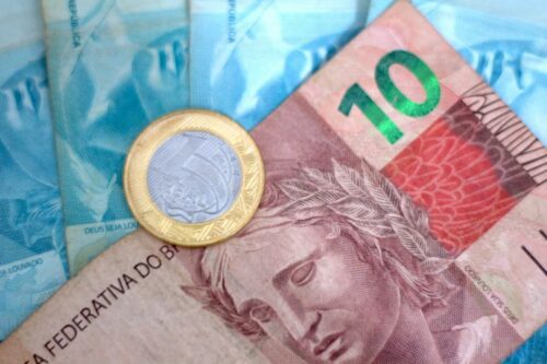 Cédulas e moeda de real brasileiro em close, simbolizando operações financeiras e atuação dos bancos no dia a dia econômico.