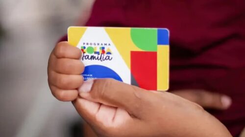 Pessoa segura cartão do Bolsa Família usado para saque e movimentação do benefício social pelo Caixa Tem.