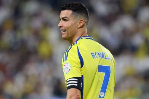 Cristiano Ronaldo sorri em campo com camisa amarela número 7 durante partida de futebol