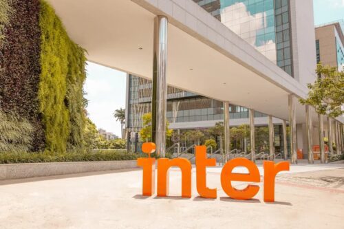 Fachada de prédio do Banco Inter com logotipo laranja em destaque na entrada do edifício comercial.