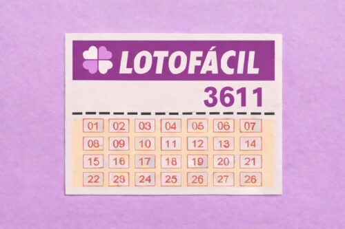 Bilhete da Lotofácil 3611 com dezenas organizadas em tabela, sobre fundo lilás.