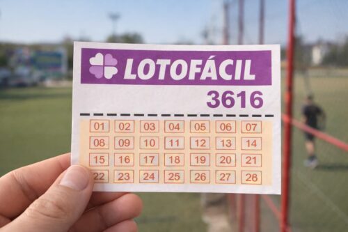Bilhete da Lotofácil 3616 com números de 01 a 28 em destaque, segurado em campo esportivo ao fundo