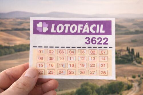 Bilhete Lotofácil 3622 segurado com paisagem rural e colinas ao fundo desfocado.