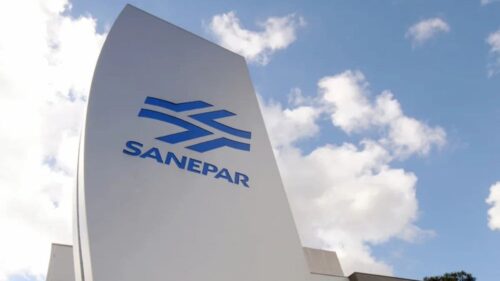 Prédio da Sanepar com logotipo azul em destaque sob céu com nuvens brancas ao fundo.
