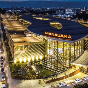 Vista aérea noturna do Manauara Shopping, em Manaus, um dos ativos estratégicos do portfólio da Allos (ALOS3). A imagem destaca a fachada iluminada e a moderna arquitetura do empreendimento urbano.
