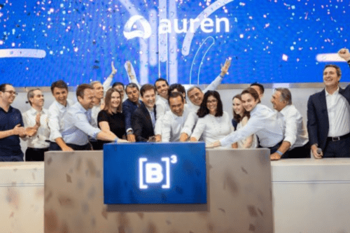 Executivos e colaboradores da Auren Energia comemoram no palco da bolsa de valores B3, em frente ao logotipo da empresa e o símbolo da [B]³, sob uma chuva de confetes durante uma cerimônia de toque de campainha.