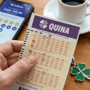 Pessoa segurando uma cartela de loteria da Quina, ao fundo uma xícara de café e moedas.